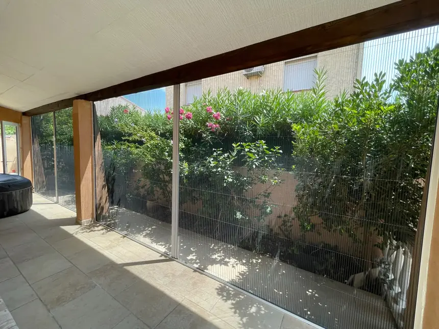 Côté de véranda entièrement fermé en moustiquaire plissée — réalisation ALUBELLE en Provence